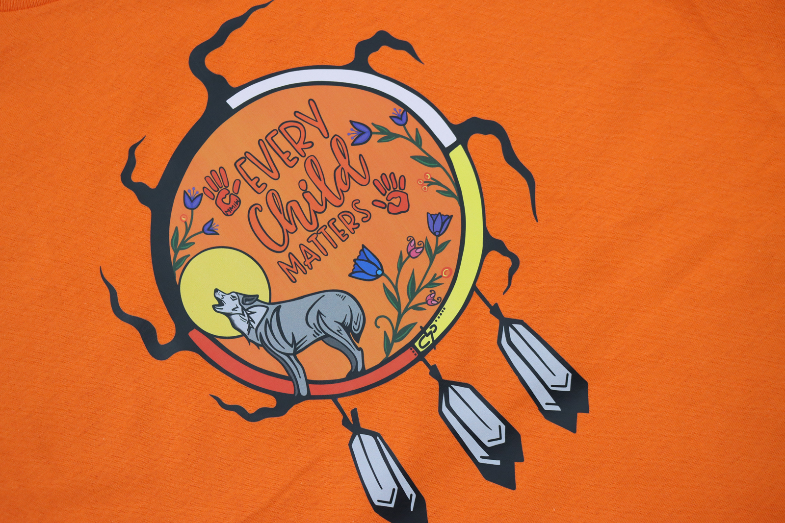 A close up of Every Child Matters artwork on an orange t-shirt