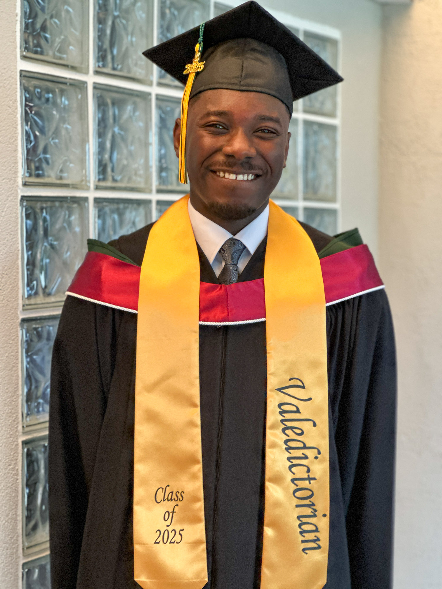 Valedictorian, Clinton Owusu happily posing in his gown and cap with Valedictorian sash draped around her neck