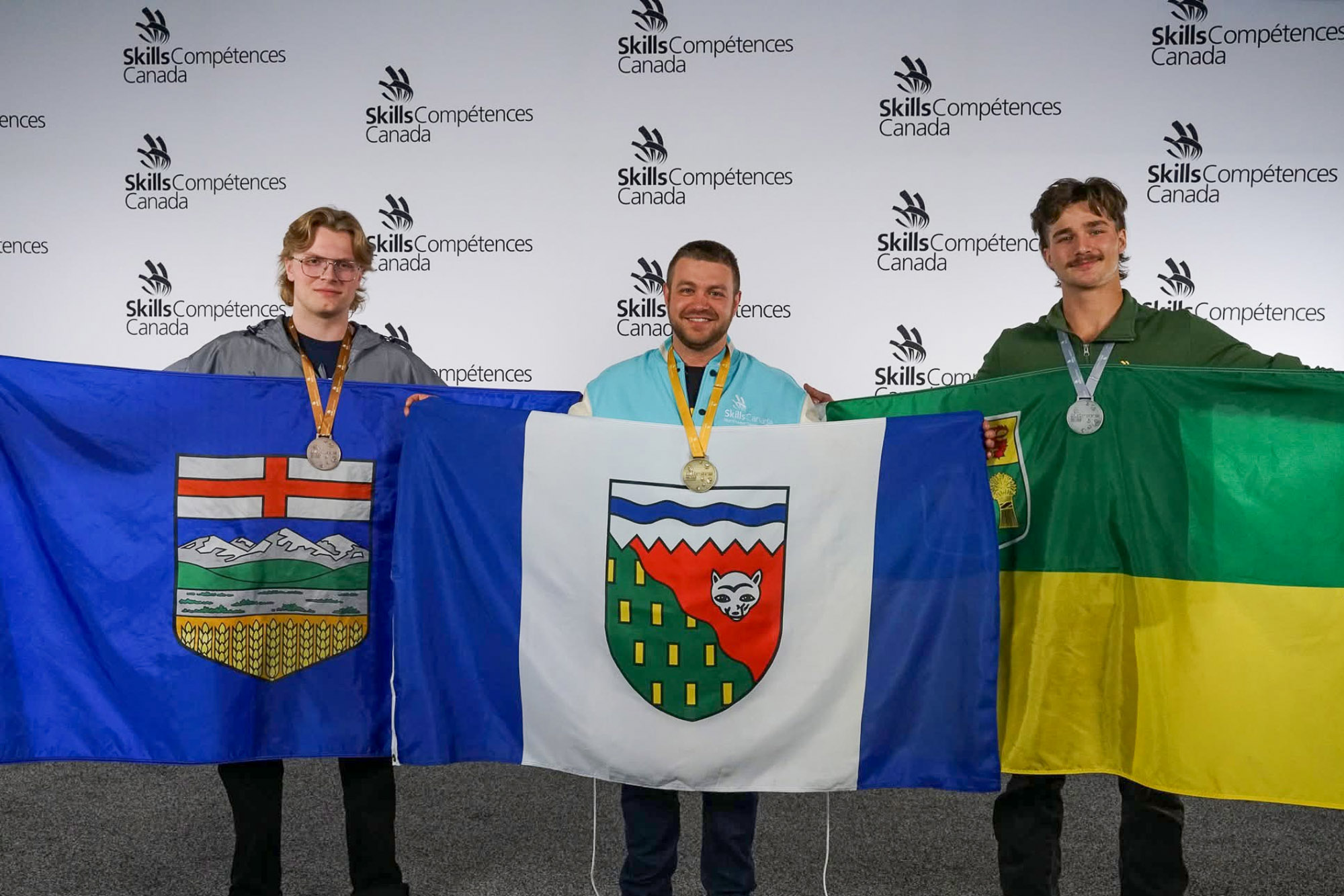 Luke Emeny holding up the Alberta flag at Skills Canada competition