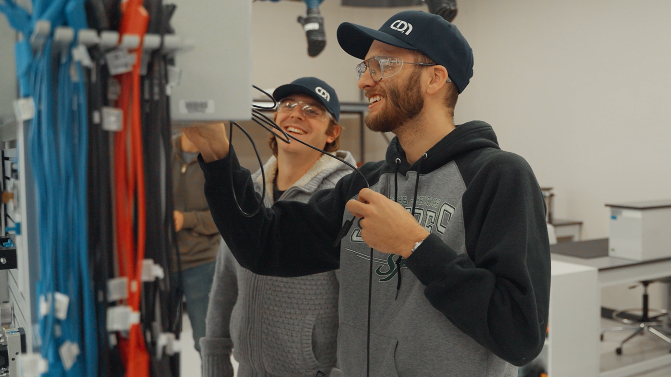 Two student in the electrical lab interacting while connecting wires in an electrical box