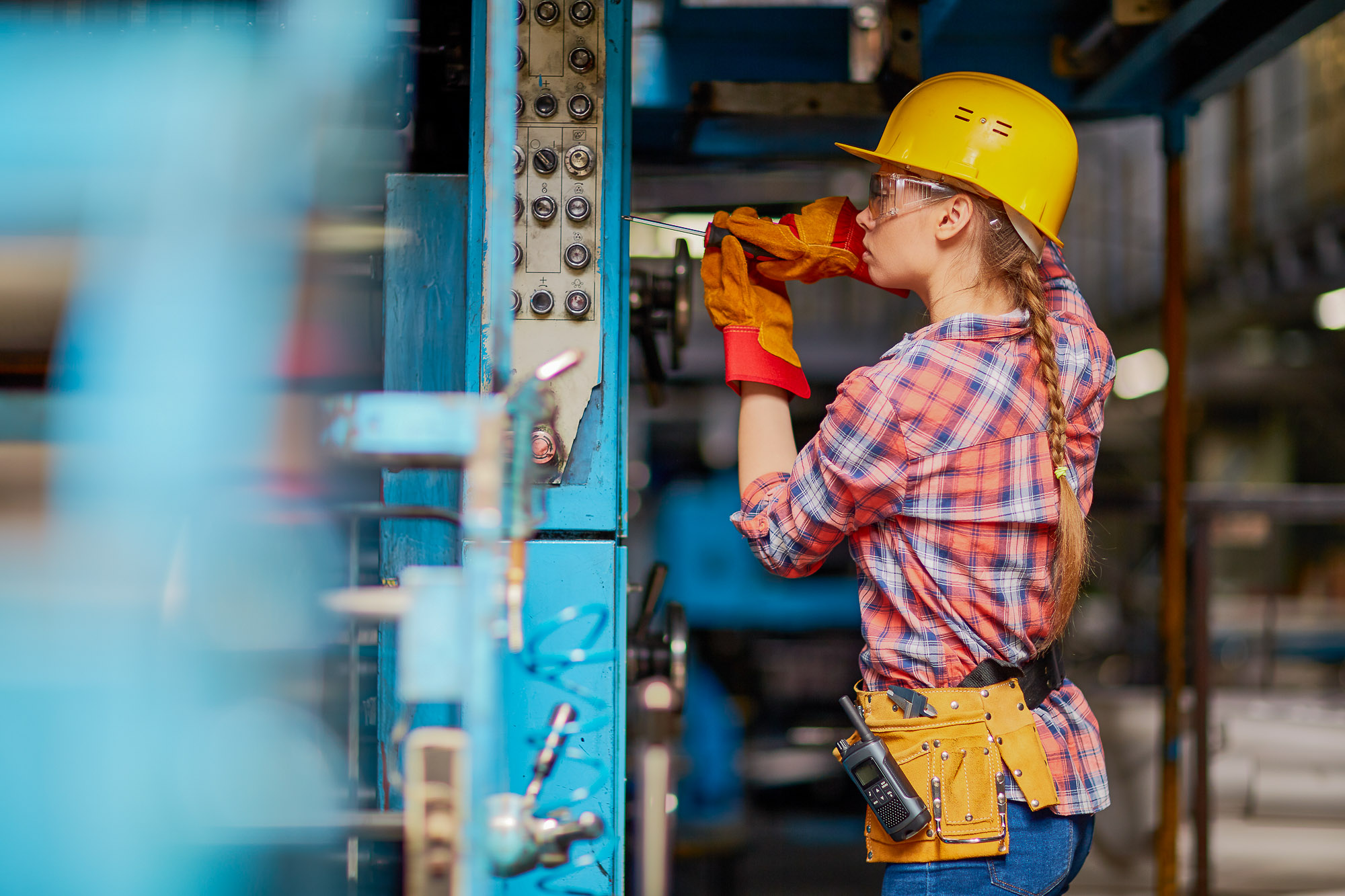 A skilled trades technician wearing safety gear works on a piece of equipment