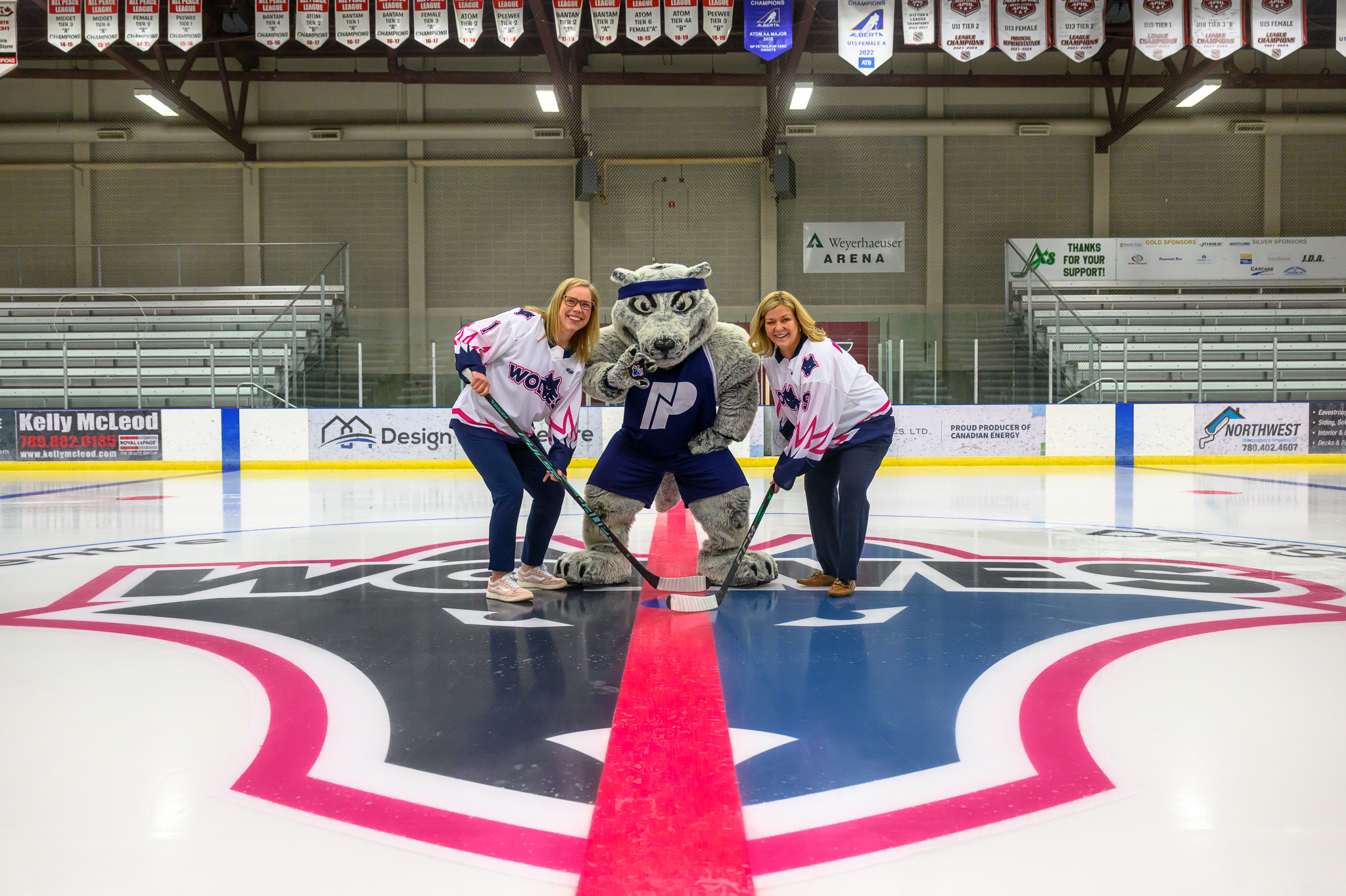 Mayor Clayton and NWP President Vanessa Sheane holding hockey sticks at centre ice with Farley the mascot