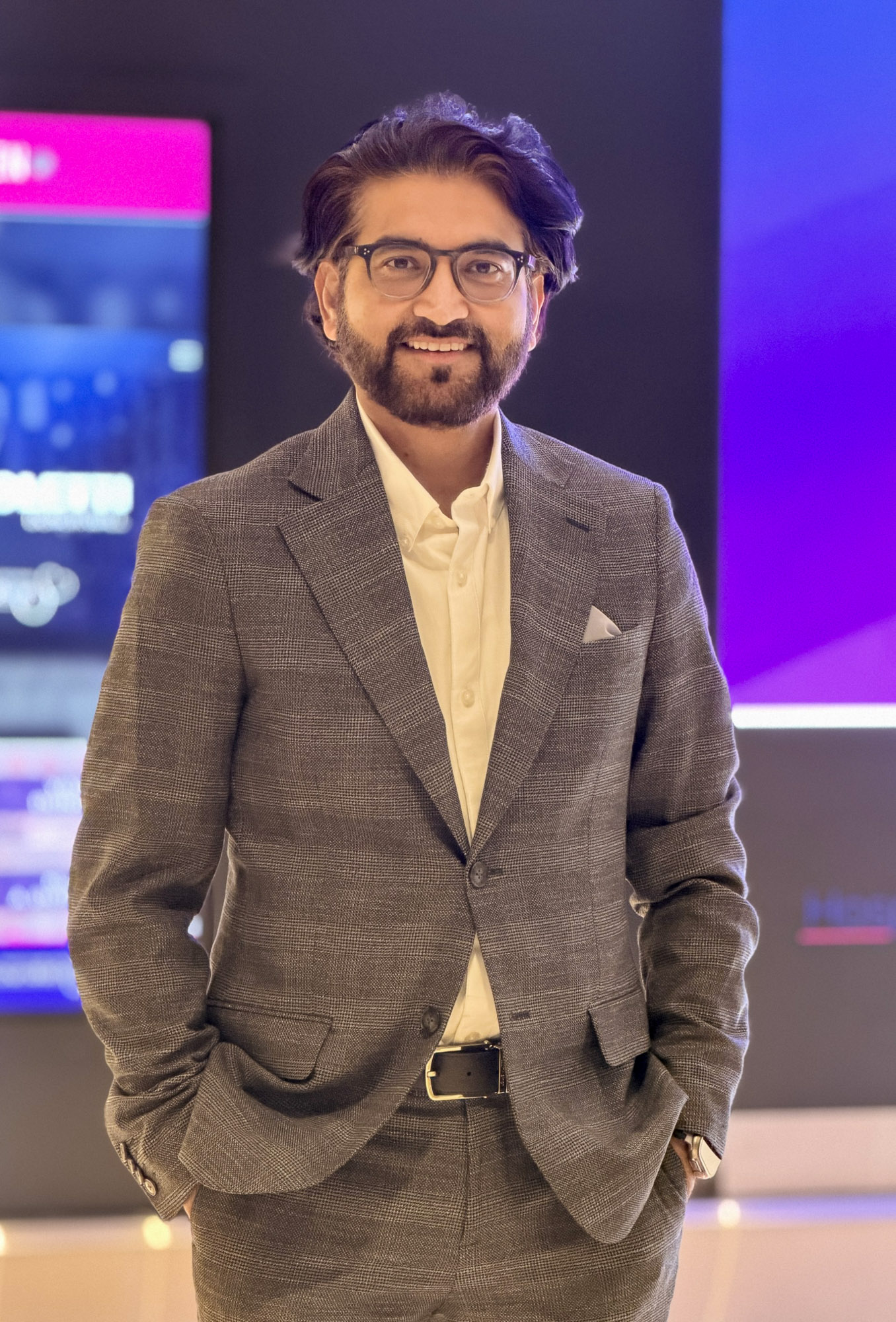 A smartly dressed Waqar smiling at the camera