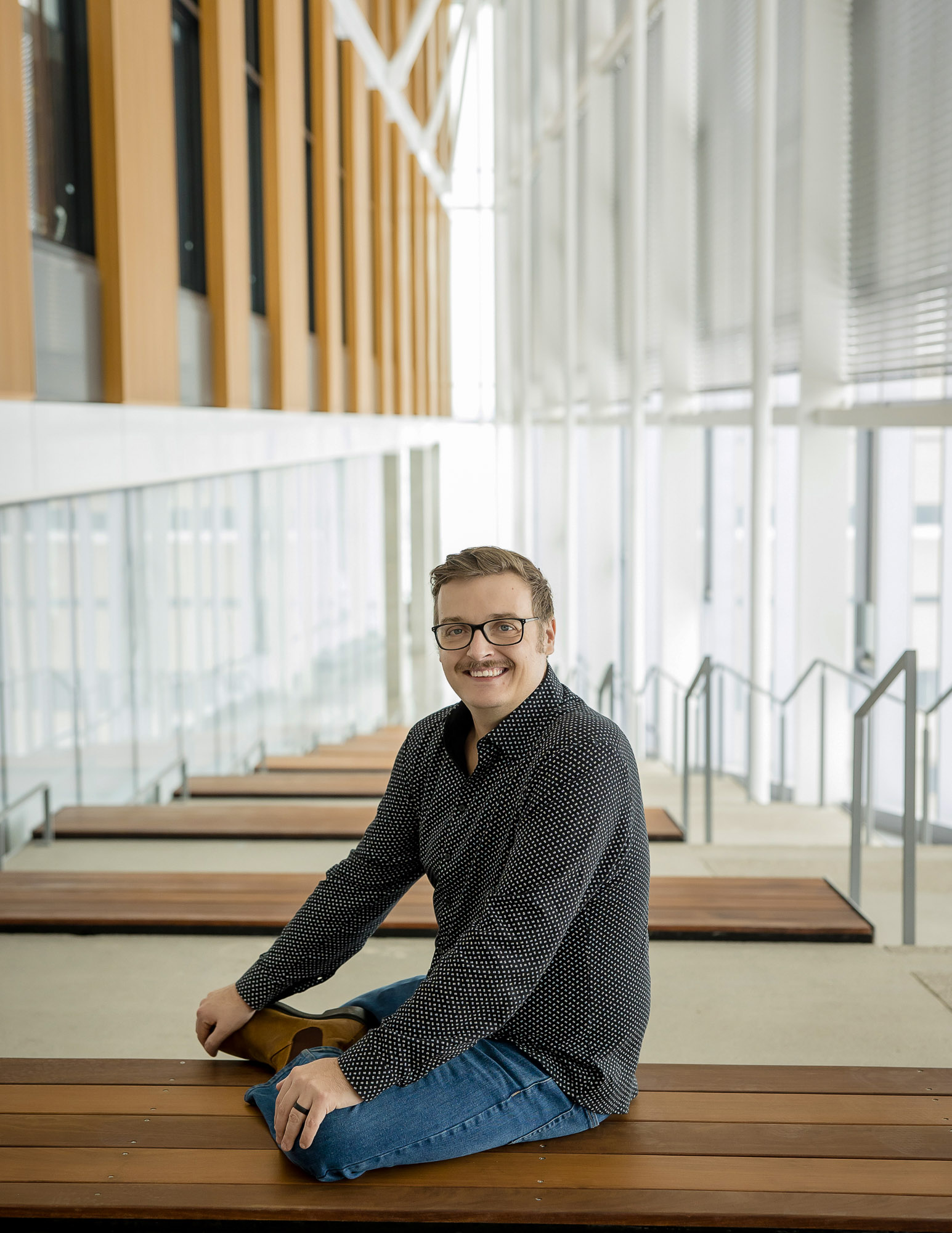Jason Bacon, Entrepreneur in Residence sitting on a bench in brightly lit assembly hall