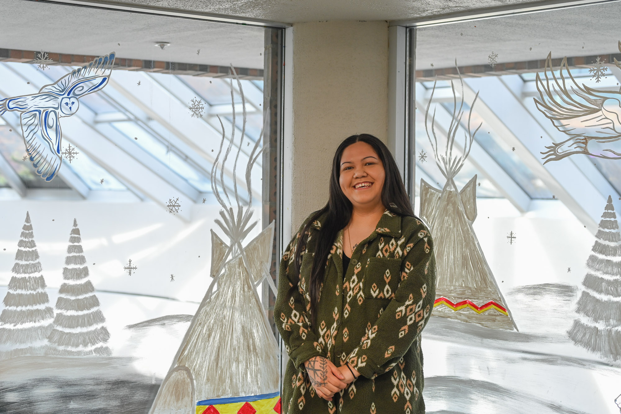 Artist, Diane Meenan standing in front of the winter scene mural she painted.