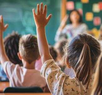 Children in a classroom with hands raised