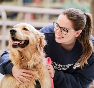 Student petting a therapy dog in the library on Grande Prairie Campus
