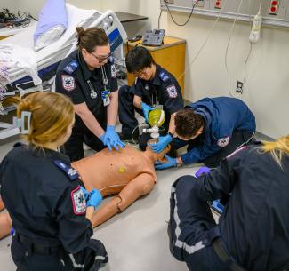 Students in emergency services providing CPR to a dummy in the simulation lab