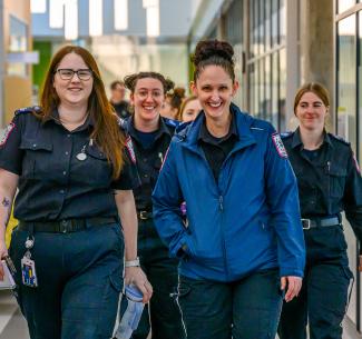 A group of happy emergency services students walking towards the camera