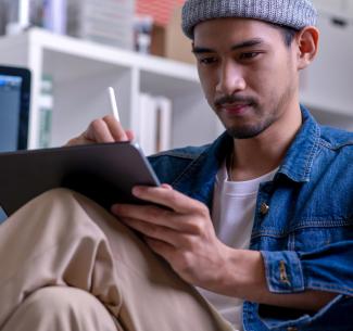 A focused graphic designer sitting and drawing on an electronic tablet