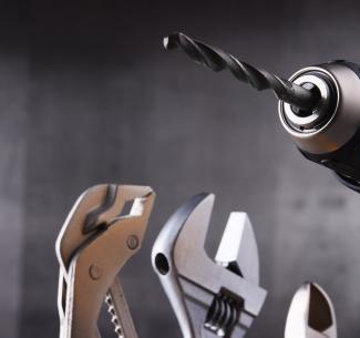 Hardware tools including cordless drill and monkey spanner used by workers in the skilled trades