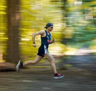 NWP Instructor, Fabio Minozzo in full stride running through a forest in the fall
