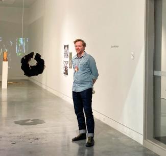 NWP visual arts instructor, David McGregor staning in an art gallery alongside his installation