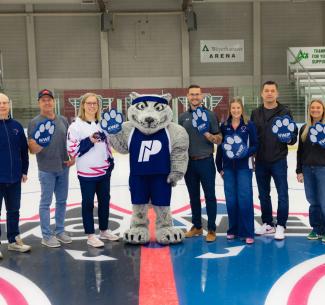 NWP and PCFAC leadership standing on centre ice at the Design Works arena waving giant foam wolf paws