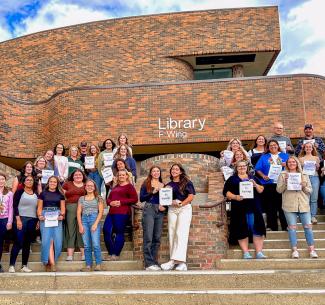 Education practicum students standing on the steps outside the F-wing entrance to NWP