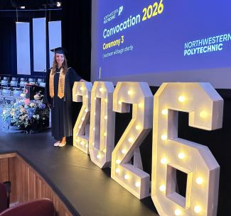 Valedictorian, Courtney Dyck in front of an illuminated 2026 sign