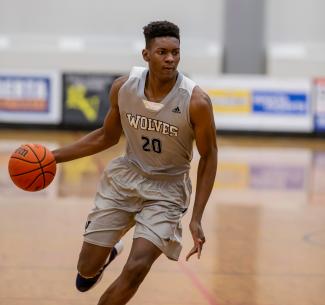 Manny Iloka wearing his #20 jersey while dribbling the ball on the basketball court