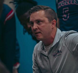 Evan Lloyd motivating the Men's Basketball team in a courtside huddle