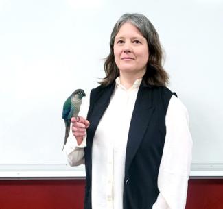 Jessie with her Green-cheeked Conure, Sapphire perched on her finger