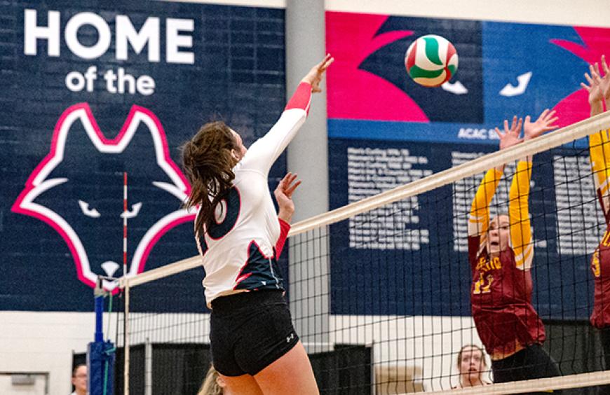 Female volleyball player hitting the ball over the net