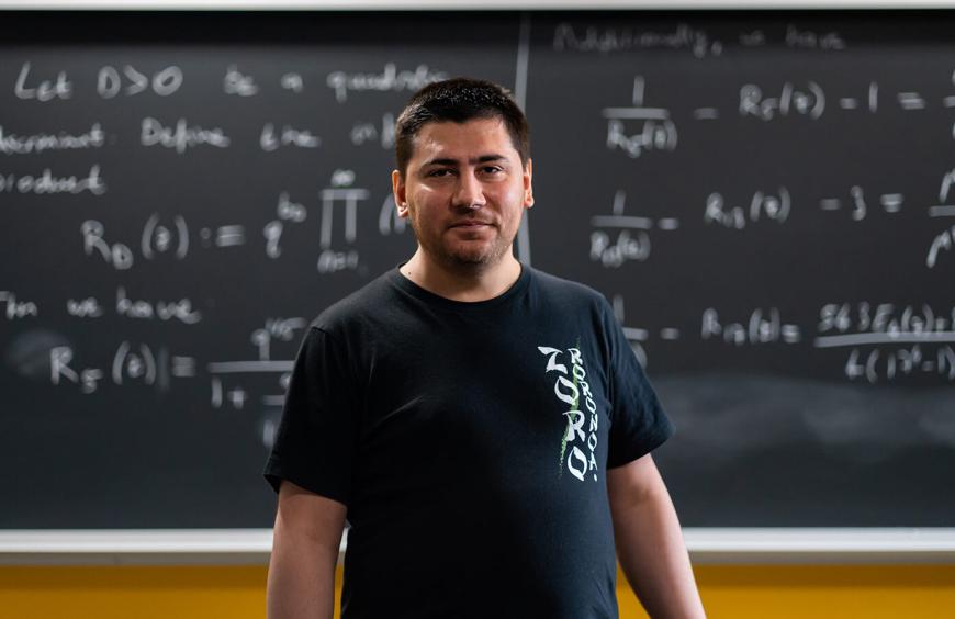Math instructor Abdel Bensouilah posing in front of chalkboard displaying algebraic equations