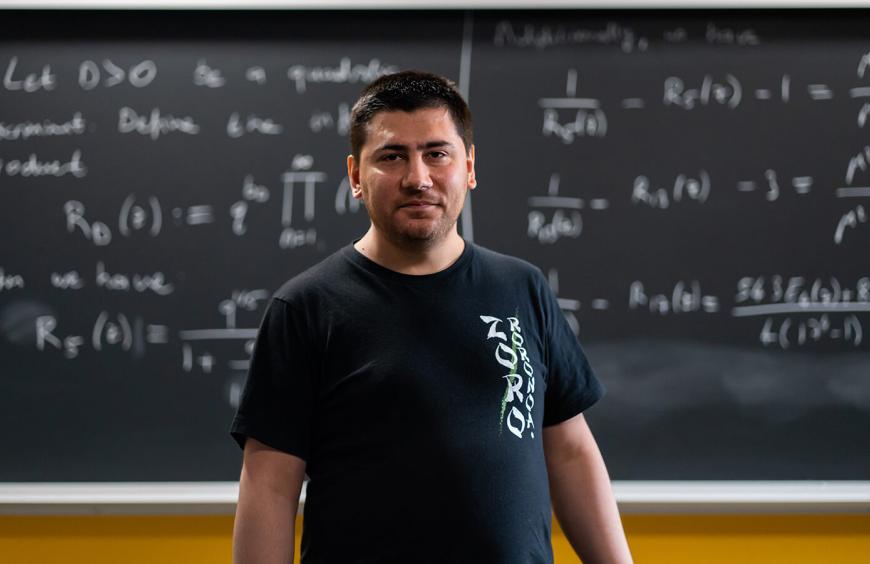Math instructor Abdel Bensouilah posing in front of chalkboard displaying algebraic equations