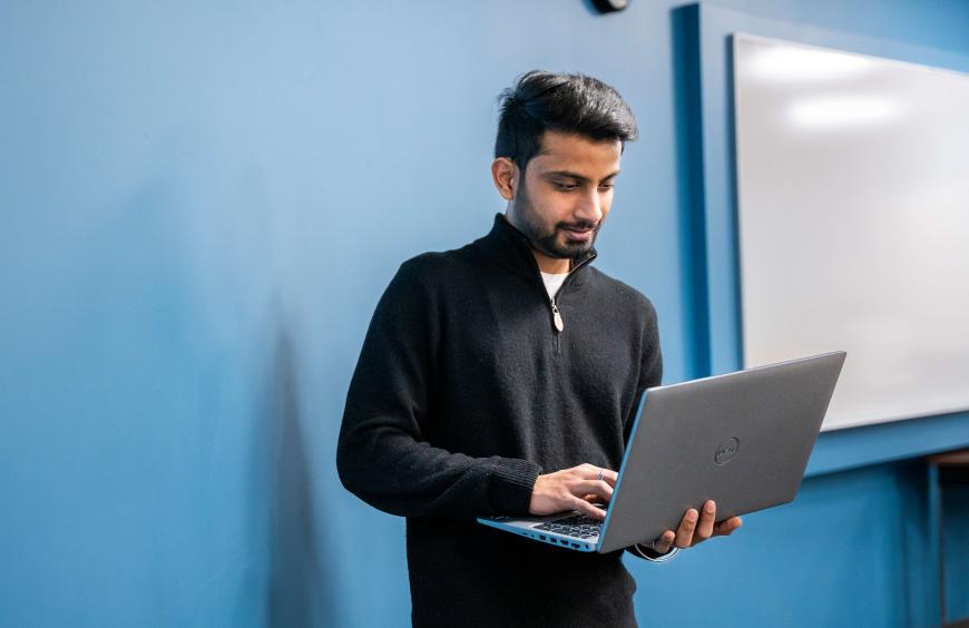Student standing up using a laptop