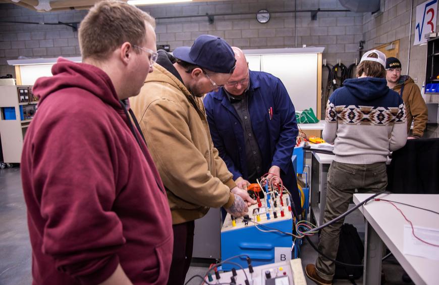 Students gathered around apparatus in the electrical lab.