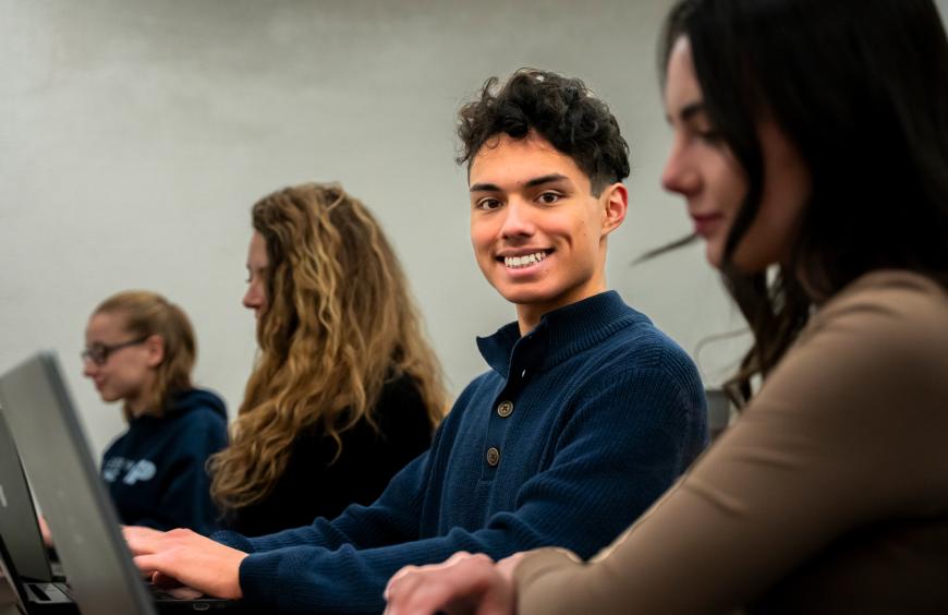 Happy student sitting in a computer lab smiling at the camera