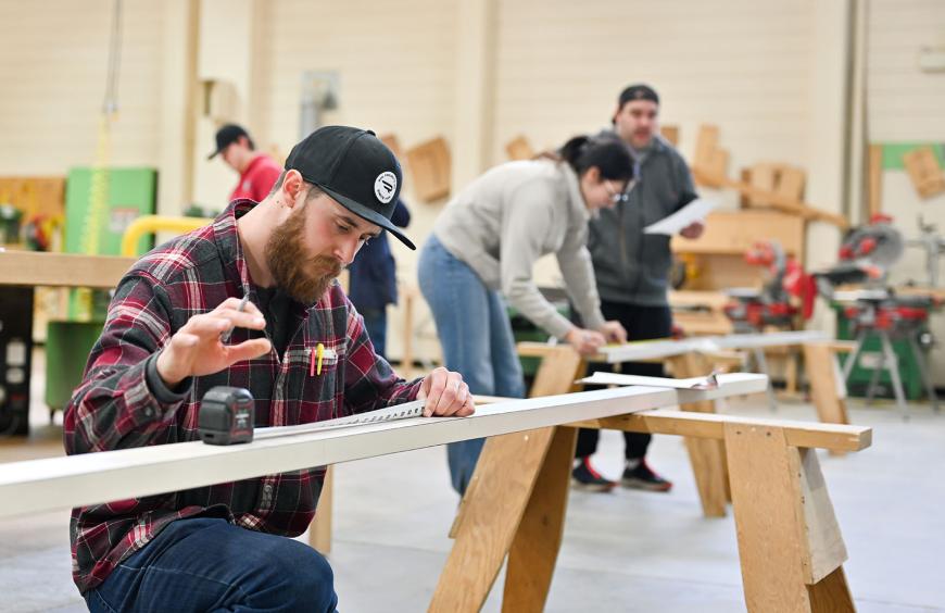Carpentry student focused on his work in a well-equipped workshop, surrounded by tools and materials