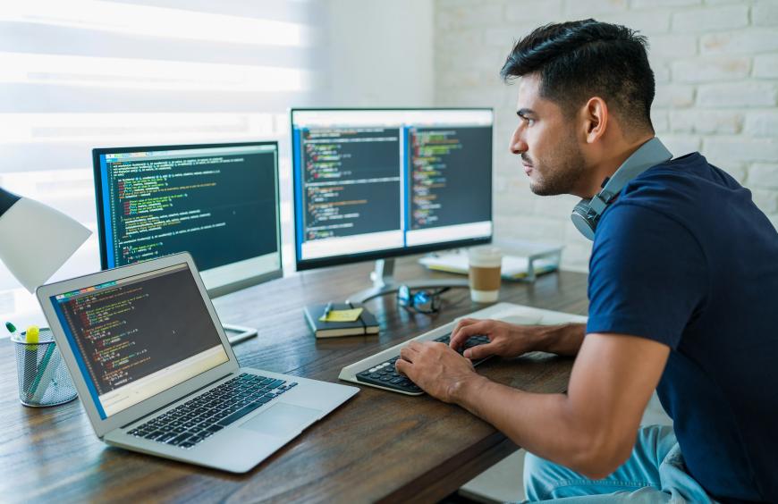 Computer programmer sitting at his desk focused on coding a program