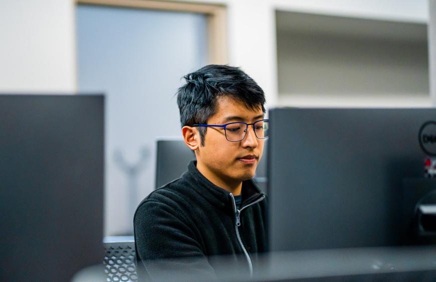 Student sitting in front of a computer and focused on programming 