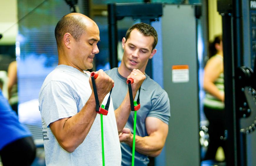 Exercise professional checking posture on a man performing a bicep pull