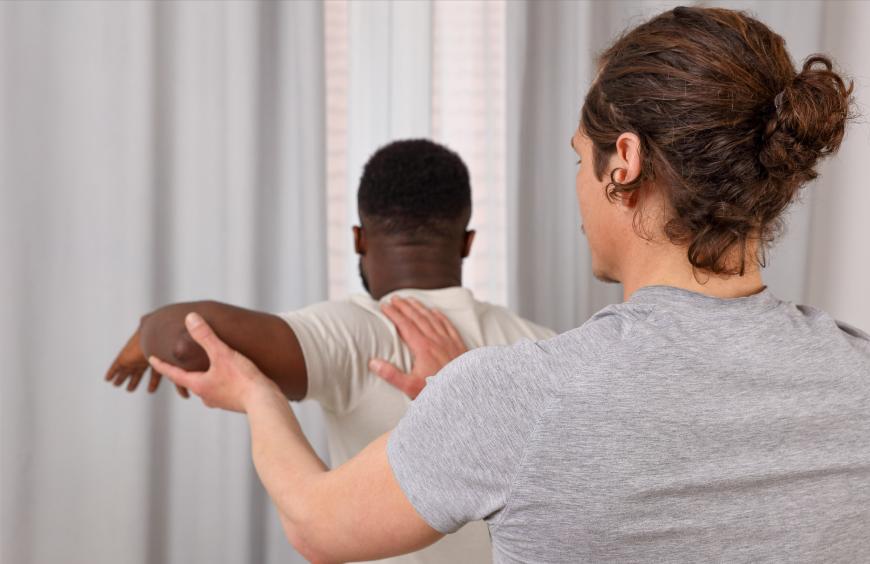 A chiropractor treating a patient by holding up the arm and extending at the elbow