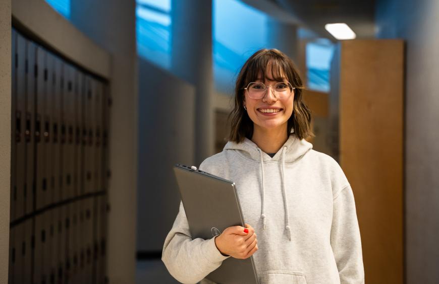 Happy student holding a laptop and walking to class