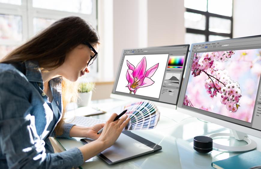 Graphic designer sitting at her computer paging through colour swatches