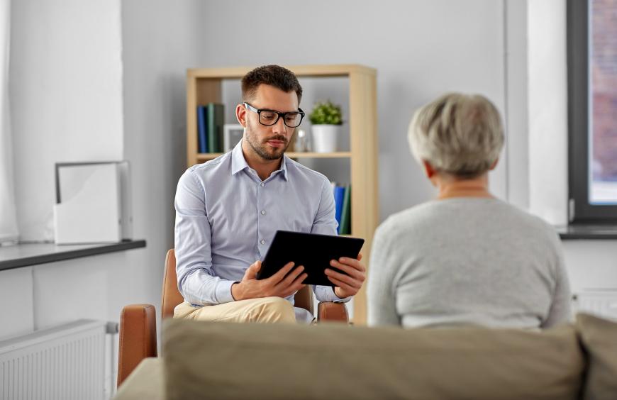 Psychologist reviewing notes on an eletronic tablet in a therapy session with an elderly client