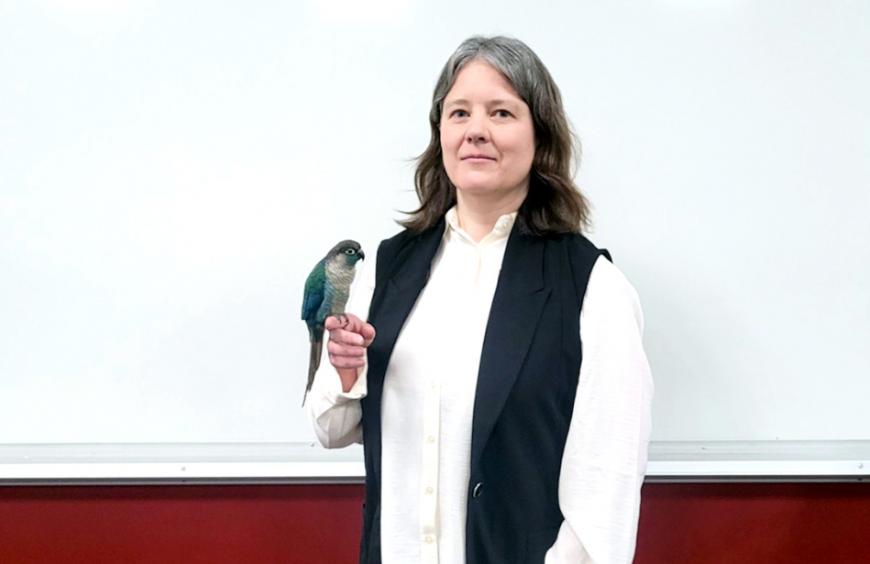 Jessie with her Green-cheeked Conure, Sapphire perched on her finger