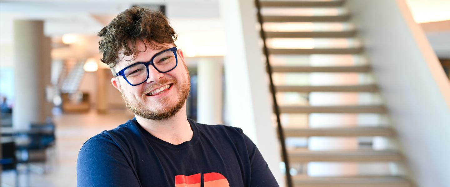 Student smiling and posing on the concourse outside the theatre on Grande Prairie campus