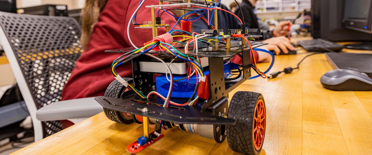 Students working on a robot with wheels in the robotics lab