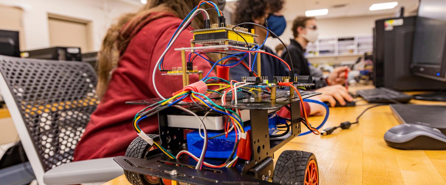 Students working on a robot with wheels in the robotics lab