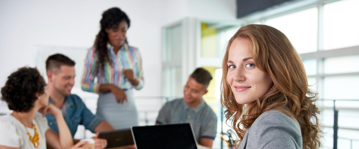 Smartly dressed woman sitting in a boardroom with professional colleagues.