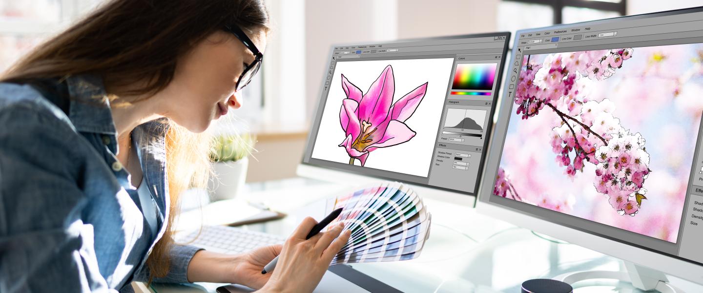 Graphic designer sitting at her computer paging through colour swatches