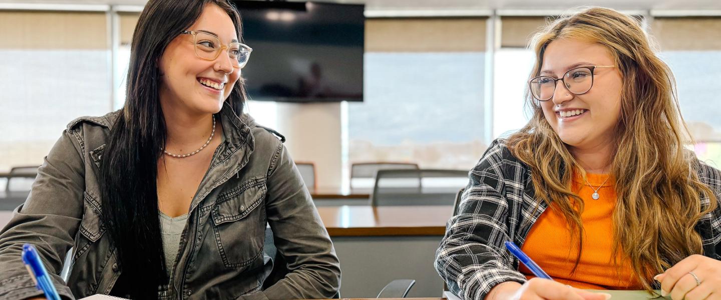 Two happy students studying in a classroom