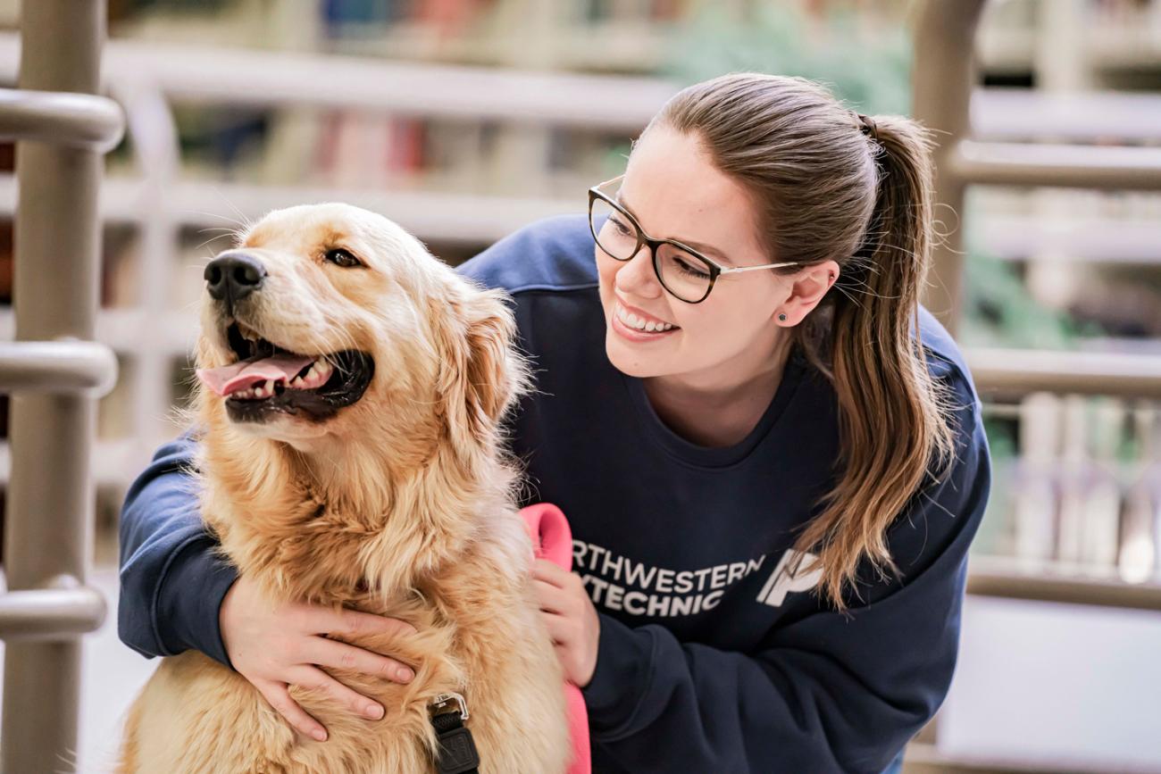 Student petting a therapy dog in the library on Grande Prairie Campus