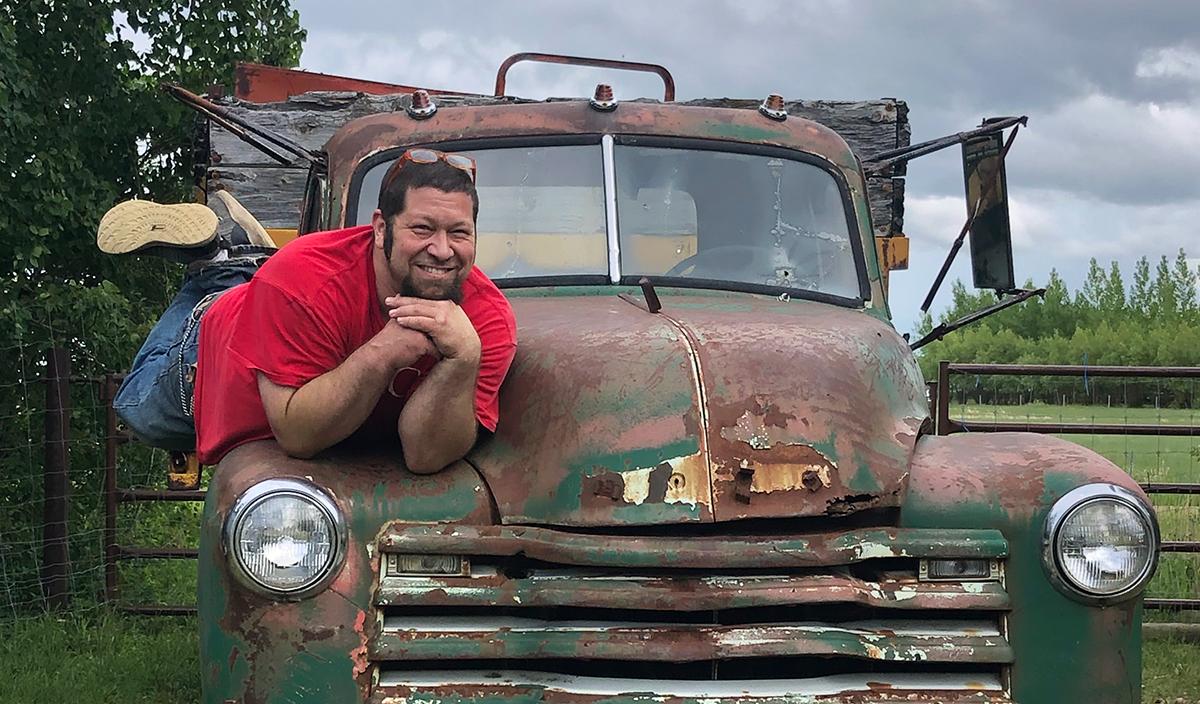 Vet tech instructor Chris Mizzi posing on the hood of an abandoned antique pickup truck