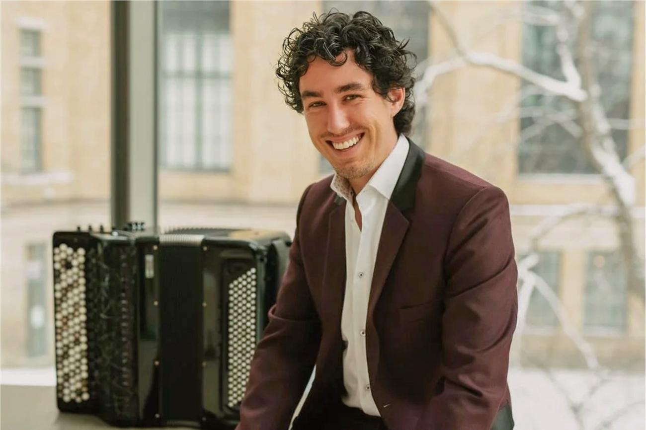 Musician Michael Bridge smiling in a pose beside his accordion