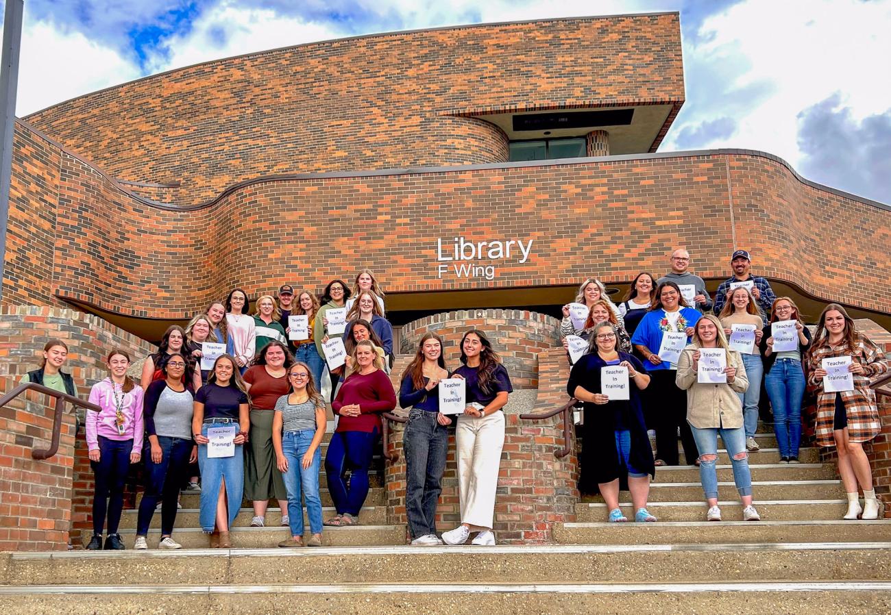 Education practicum students standing on the steps outside the F-wing entrance to NWP