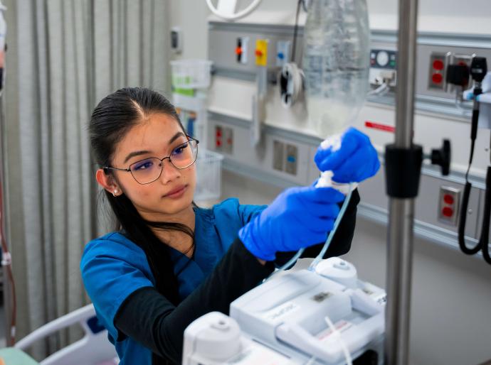 Nursing student hanging a bag of saline