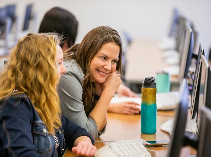 Student at a computer getting help from a staff member